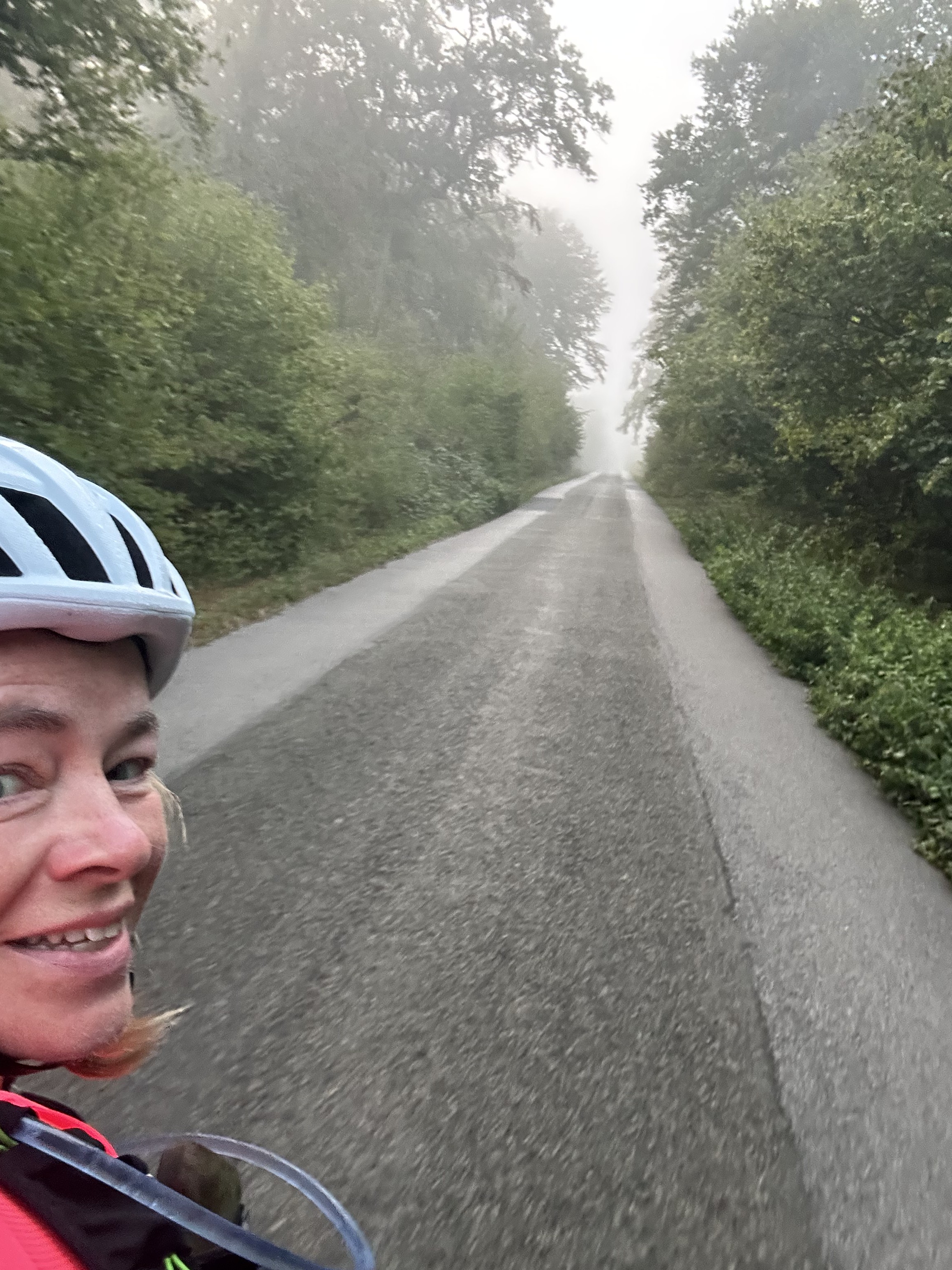 Katrina Gwynne-Jones smiling in a selfie on a wet road during the London to Paris cycle